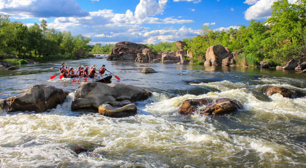 Exciting white water rafting adventure with a group of people navigating through rapids in an inflatable raft, surrounded by splashing water and lush greenery under a bright sky, conveying a sense of thrill and teamwork.